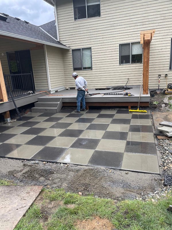 Worker installing checkered concrete patio tiles