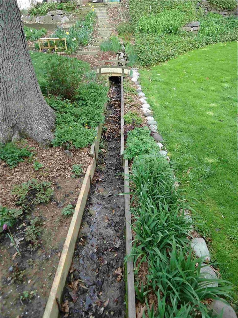 Wooden garden path through lush green garden.