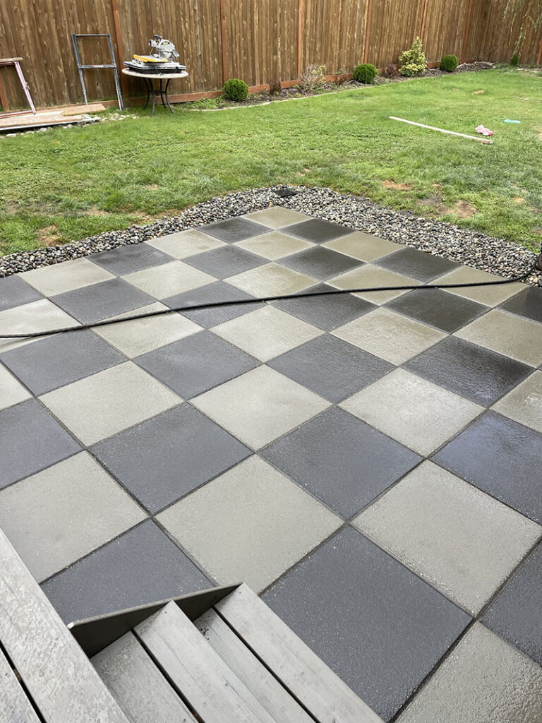 Patterned patio tiles in a backyard garden setting.
