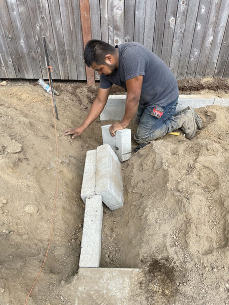 Man installing concrete blocks for landscaping.