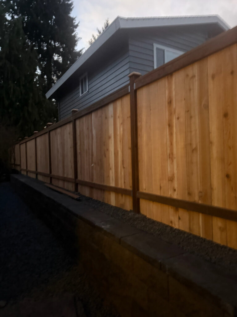 wooden fence installation next to a retaining wall we created out in snohomish county washington