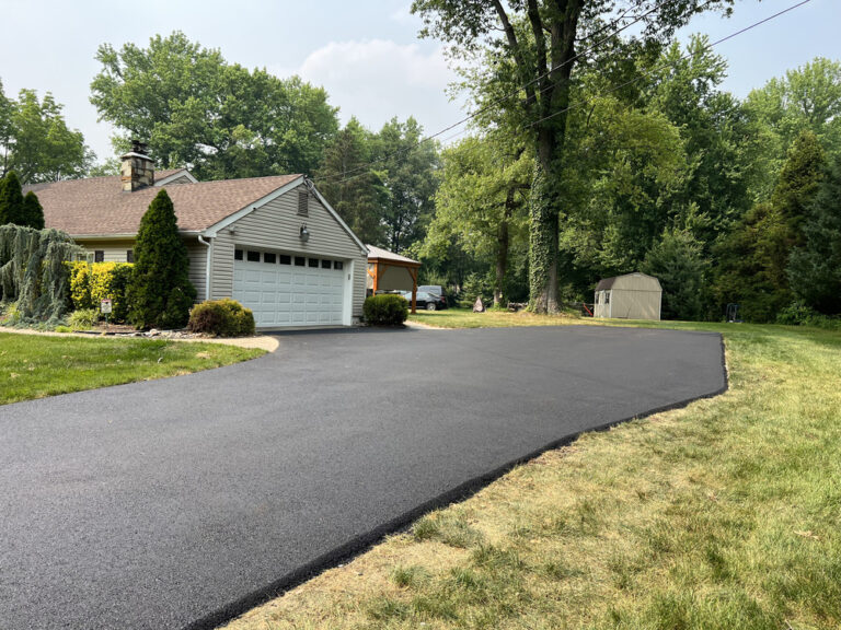 Freshly paved asphalt driveway beside suburban house