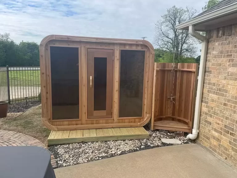 Outdoor wooden sauna beside brick house